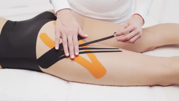 치료가는 여성의 몸에 방추사 테이프를 적용하고 있습니다. 물리 요법, 동역학 및 회복 요법. — 비디오