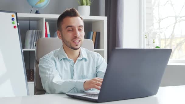 Młody Nauczyciel udziela lekcji online siedząc przed komputerem w domu. Miejsce pracy Korepetytora Lekcji Szkolnych. Koncepcja odległej nauki i edukacji. — Wideo stockowe