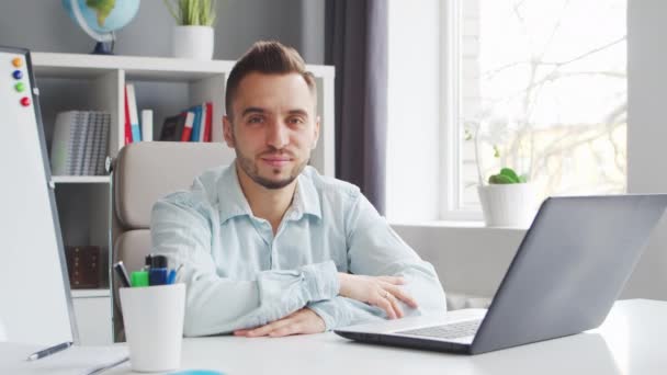 Young Teacher hace una lección en línea mientras está sentado frente a la computadora en casa. El lugar de trabajo del tutor para las lecciones escolares. Concepto de estudio y educación a distancia. — Vídeo de stock