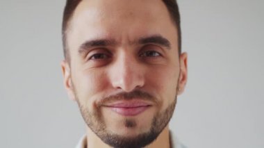 Genç Kafkasyalı Brunet Adam Açık Gri Arkaplanda Kameraya Bakıyor. Stüdyo Erkek Yüz Portresi. Doğal Gün Işığı.