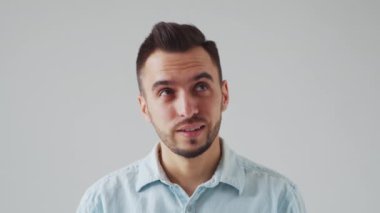 Genç Kafkasyalı Brunet Adam Açık Gri Arkaplanda Kameraya Bakıyor. Stüdyo Erkek Yüz Portresi. Doğal Gün Işığı.