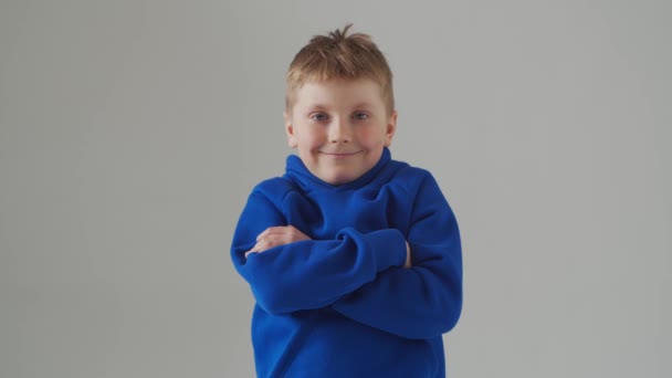 Portret uśmiechniętego chłopca w niebieskiej koszulce. Atrakcyjne dziecko w studiu nad szarością. — Wideo stockowe