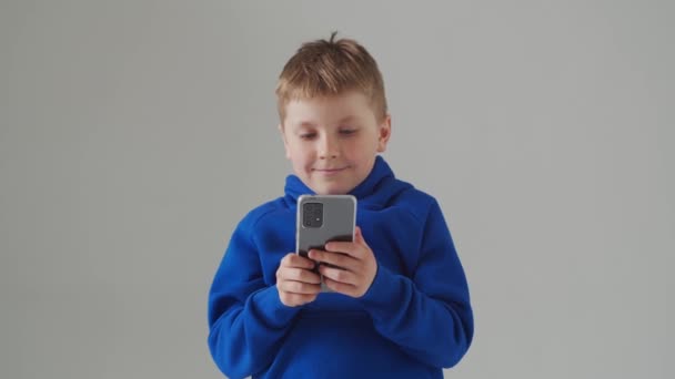 Πορτρέτο του χαρούμενου χαμογελαστού αγοριού με το μπλε μπλουζάκι. Ελκυστικό παιδί σε στούντιο πάνω από γκρι. — Αρχείο Βίντεο