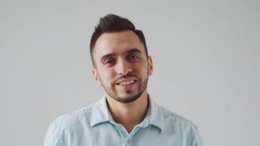 Genç Kafkasyalı Brunet Adam Açık Gri Arkaplanda Kameraya Bakıyor. Stüdyo Erkek Yüz Portresi. Doğal Gün Işığı.