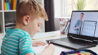 Çocuk Masa 'da ödevini yapıyor. Şirin Çocuk Laptop Bilgisayar ve Okul Ders Kitapları 'nın yardımıyla Evde Öğreniyor. Eğitim ve Uzaktan Eğitim Konsepti.