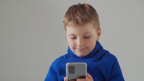Portret van vrolijke lachende jongen in blauw t-shirt. Aantrekkelijk kind in studio over grijs. — Stockvideo
