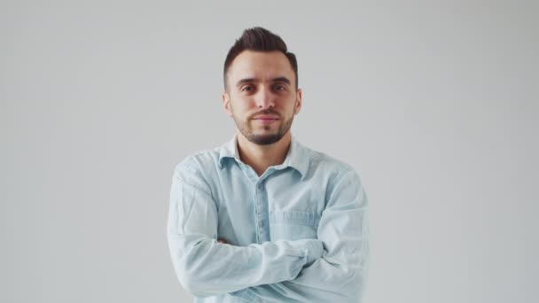 Junger kaukasischer Brunet-Mann blickt vor hellgrauem Hintergrund in die Kamera. Studio Male Face Portrait. Natürliches Tageslicht. — Stockvideo