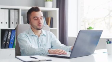 Genç adam evde bir bilgisayarın önünde otururken çalışıyor. Profesyonel bir işçinin, serbest çalışanın ya da öğrencinin işyeri. Mesafe Çalışma ve Eğitim Konsepti.