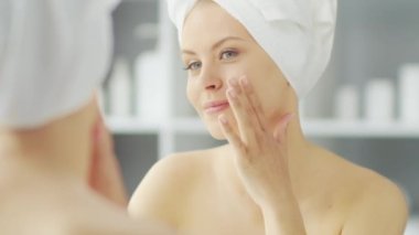 Genç Kız, Tuvalette Makyaj Aynası 'nın önünde oturuyor ve cilt kremi sürüyor. Güzel kadın kozmetik yenileme prosedürleri uyguluyor. Sağlık ve Güzellik Konsepti.