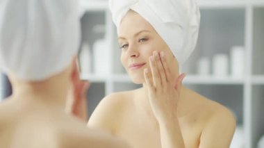 Genç Kız, Tuvalette Makyaj Aynası 'nın önünde oturuyor ve cilt kremi sürüyor. Güzel kadın kozmetik yenileme prosedürleri uyguluyor. Sağlık ve Güzellik Konsepti.