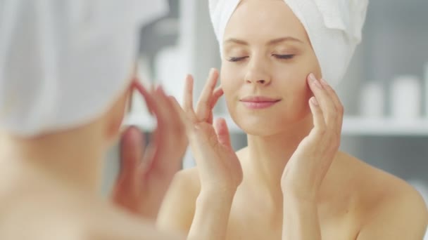 小女孩正坐在浴室的化妆品镜子前 涂着护肤霜 美丽的女人正在做整形手术 健康与美的概念 — 图库视频影像