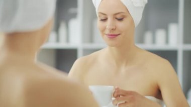 Genç Kız, Tuvalette Makyaj Aynası 'nın önünde oturuyor ve cilt kremi sürüyor. Güzel kadın kozmetik yenileme prosedürleri uyguluyor. Sağlık ve Güzellik Konsepti.