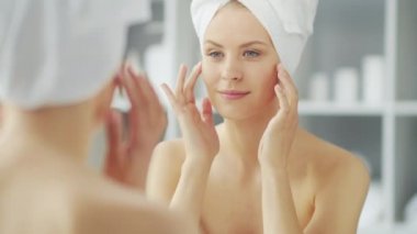 Genç Kız, Tuvalette Makyaj Aynası 'nın önünde oturuyor ve cilt kremi sürüyor. Güzel kadın kozmetik yenileme prosedürleri uyguluyor. Sağlık ve Güzellik Konsepti.