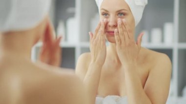 Genç Kız, Tuvalette Makyaj Aynası 'nın önünde oturuyor ve cilt kremi sürüyor. Güzel kadın kozmetik yenileme prosedürleri uyguluyor. Sağlık ve Güzellik Konsepti.