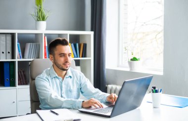 Genç adam evde bir bilgisayarın önünde otururken çalışıyor. Profesyonel bir işçinin, serbest çalışanın ya da öğrencinin işyeri. Mesafe Çalışma ve Eğitim Konsepti.