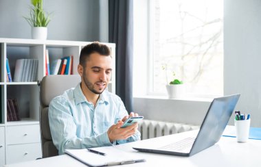 Young Man Works while Sitting in front of a Computer at Home. The Workplace of a Professional Worker, Freelancer or Student. The Concept of Distance Work and Education.