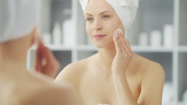 Genç Kız, Tuvalette Makyaj Aynası 'nın önünde oturuyor ve cilt kremi sürüyor. Güzel kadın kozmetik yenileme prosedürleri uyguluyor. Sağlık ve Güzellik Konsepti.
