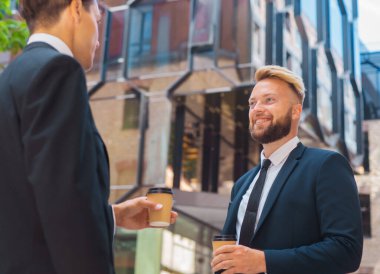 Modern ofis binasının önünde kendinden emin bir iş adamı ve meslektaşı. Formalite yatırımcıları dışarıda konuşuyorlar. Bankacılık ve iş konsepti.