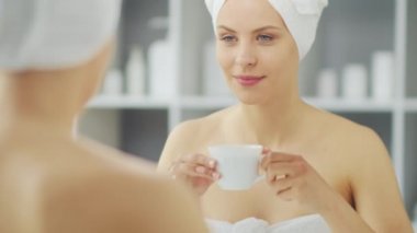 Genç Kız, Tuvalette Makyaj Aynası 'nın önünde oturuyor ve cilt kremi sürüyor. Güzel kadın kozmetik yenileme prosedürleri uyguluyor. Sağlık ve Güzellik Konsepti.