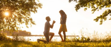 Sevgi dolu bir adam güzel kız arkadaşına düğün teklifi yapıyor. Karım ol konsepti. Alan ve deniz arkaplanı.