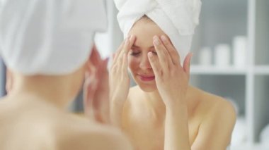 Genç Kız, Tuvalette Makyaj Aynası 'nın önünde oturuyor ve cilt kremi sürüyor. Güzel kadın kozmetik yenileme prosedürleri uyguluyor. Sağlık ve Güzellik Konsepti.