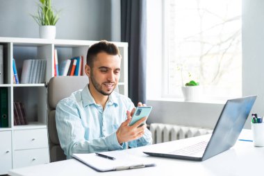 Young Man Works while Sitting in front of a Computer at Home. The Workplace of a Professional Worker, Freelancer or Student. The Concept of Distance Work and Education.