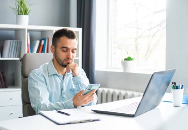 Young Man Works while Sitting in front of a Computer at Home. The Workplace of a Professional Worker, Freelancer or Student. The Concept of Distance Work and Education.