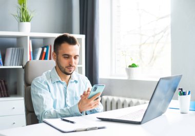 Young Man Works while Sitting in front of a Computer at Home. The Workplace of a Professional Worker, Freelancer or Student. The Concept of Distance Work and Education.