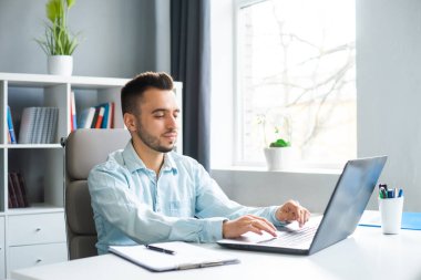 Genç adam evde bir bilgisayarın önünde otururken çalışıyor. Profesyonel bir işçinin, serbest çalışanın ya da öğrencinin işyeri. Mesafe Çalışma ve Eğitim Konsepti.