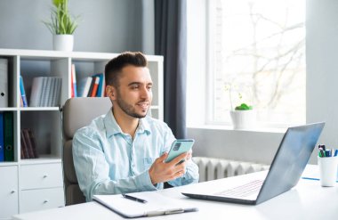 Young Man Works while Sitting in front of a Computer at Home. The Workplace of a Professional Worker, Freelancer or Student. The Concept of Distance Work and Education.