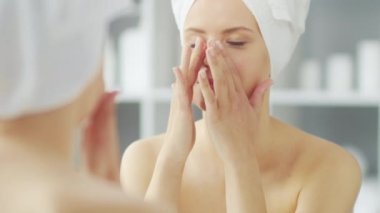 Genç Kız, Tuvalette Makyaj Aynası 'nın önünde oturuyor ve cilt kremi sürüyor. Güzel kadın kozmetik yenileme prosedürleri uyguluyor. Sağlık ve Güzellik Konsepti.