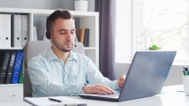 Young Man Works while Sitting in front of a Computer at Home. The Workplace of a Professional Worker, Freelancer or Student. The Concept of Distance Work and Education.