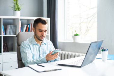Young Man Works while Sitting in front of a Computer at Home. The Workplace of a Professional Worker, Freelancer or Student. The Concept of Distance Work and Education.