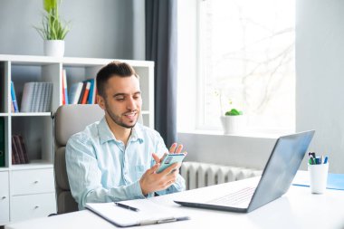 Young Man Works while Sitting in front of a Computer at Home. The Workplace of a Professional Worker, Freelancer or Student. The Concept of Distance Work and Education.