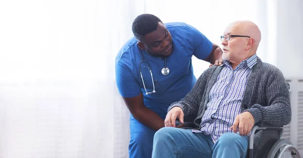 Professional doctor helps an elderly man with chronic diseases. Therapist and patient in home interior. The concept of health care and medicine.