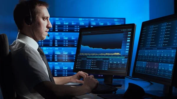 Broker works in office using workstation and analysis technology. Workplace of professional trader. Global financial markets, business strategy, currency exchange and banking concepts.
