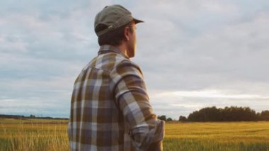 Farmer in front of a sunset agricultural landscape. Man in a countryside field. The concept of country life, food production, farming and country lifestyle.