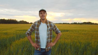 Günbatımı tarımının önündeki çiftçi. Kırsal kesimde bir adam. Kır hayatı, gıda üretimi, tarım ve kırsal yaşam tarzı kavramı.