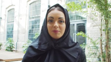 Portrait of young and confident Muslim business woman in hijab. Middle Eastern office worker or businesswoman is working outdoor in the city. Corporate and financial concept.