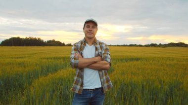 Günbatımı tarımının önündeki çiftçi. Kırsal kesimde bir adam. Kır hayatı, gıda üretimi, tarım ve kırsal yaşam tarzı kavramı.