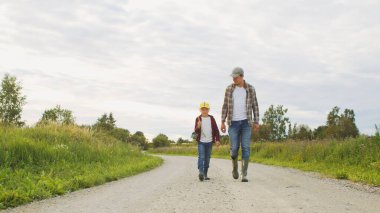 Çiftçi ve oğlu günbatımı tarımının önünde. Kırsalda bir adam ve bir çocuk. Babalık kavramı, köy hayatı, tarım ve kırsal yaşam tarzı..