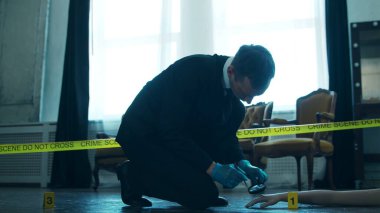 Detective Collecting Evidence in a Crime Scene. Forensic Specialists Making Expertise at Home of a Dead Person. The Concept of Homicide Investigation by Professional Police Officer.