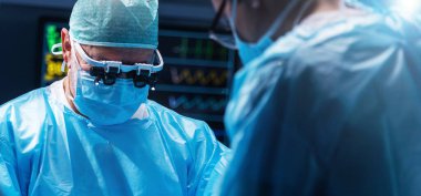 Diverse team of professional medical surgeons perform surgery in the operating room using high-tech equipment. Doctors work to save a patient in a modern hospital. The concept of medicine, technology
