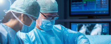 Diverse team of professional medical surgeons perform surgery in the operating room using high-tech equipment. Doctors work to save a patient in a modern hospital. The concept of medicine, technology