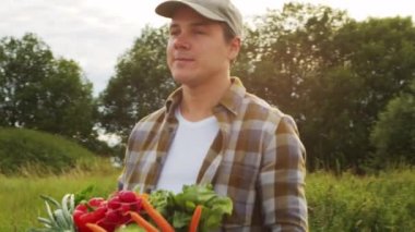 Sebze kutusu olan bir çiftçi. Kırsal alanda yürüyen bir adam. Kır hayatı, gıda üretimi, tarım ve kırsal yaşam tarzı kavramı.