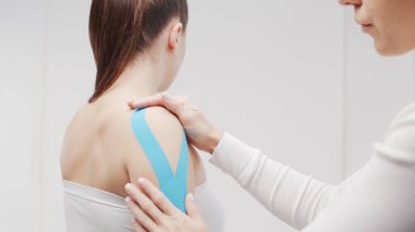 Therapist is applying tape to beautiful female body. Physiotherapy, kinesiology and recovery treatment.