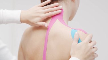 Therapist is applying tape to beautiful female body. Physiotherapy, kinesiology and recovery treatment.