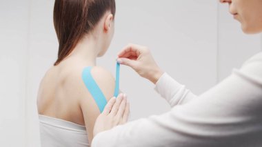Therapist is applying tape to beautiful female body. Physiotherapy, kinesiology and recovery treatment.
