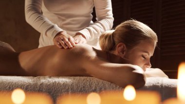Genç, sağlıklı ve güzel bir kadın spa salonunda masaj terapisi görüyor. Sağlıklı yaşam tarzı ve vücut bakımı kavramı.