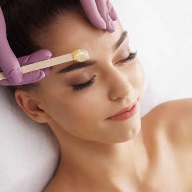 The concept of hair removal, beauty and health. A young girl is getting an epilation procedure. A processional beauty worker is making depilation with hot wax.